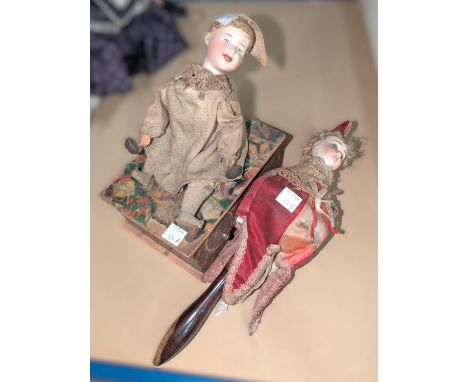 A 19th century bisque headed German doll on swivelling stick, and a bisque headed doll sitting on a musical box.