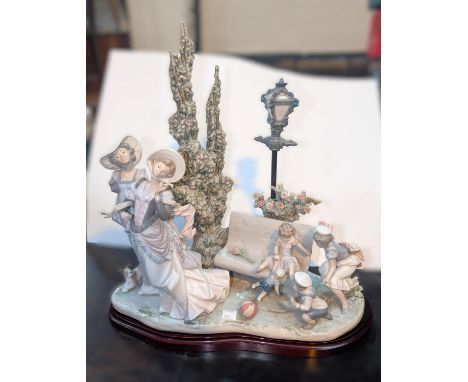 A Lladro group, garden scene with two women and children playing on a bench, ht. 41cm (parasol missing)Condition report:The g