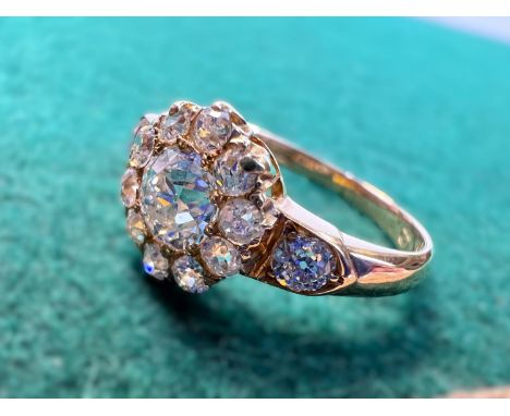 A lady's yellow metal dress ring set with central old cut diamond,  approx. 0.5ct surrounded by 10 smaller diamonds in flower