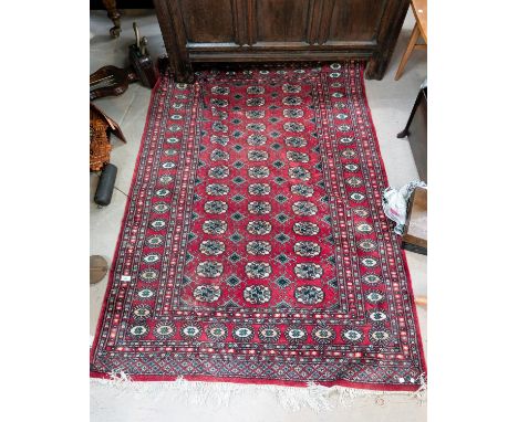 A red ground 20th Century hand knotted Middle Eastern carpet with three rows of central medallions.