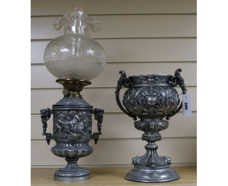 A 19th century silvered metal two handled vase and an oil lamp cast with bacchanalians, (2)