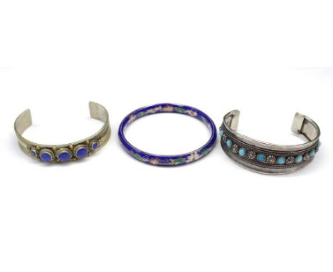 A group of three bangles includes a silver example set with turquoise simulants, a cloisonne and tribal bangle set with lapis