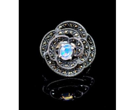 Opal and silver flower ring set with a oval crystal opal and a halo of marcasite in a flower petal and leaf shoulders. Marked