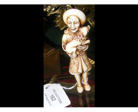 An antique Japanese ivory netsuke depicting a Dutchman holding a puppy in both hands - 9.5cm CONDITION REPORTseems in good co