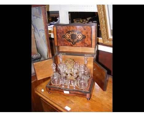 A 19th century inlaid walnut liqueur decanter glass set, containing four decanters and thirteen glasses with engraved decorat