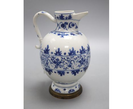 A Chinese blue and white ewer, Kangxi period, with a later brass mounted foot, 22cm high