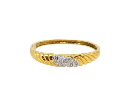 An 18ct gold diamond set bangle, scalloped front section with a central swirl of round brilliant cut diamonds, estimated appr