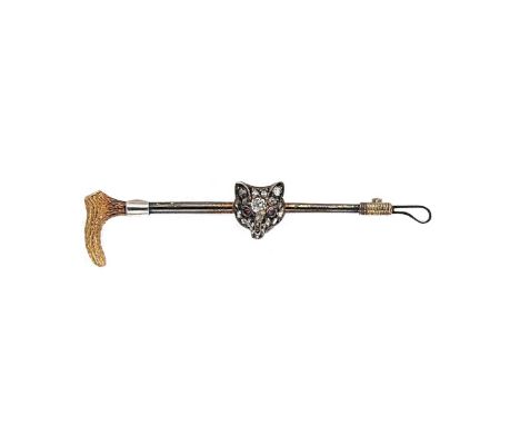 A diamond and ruby set fox head and riding crop brooch, the realistically formed fox head set with rose cut diamonds and rubi
