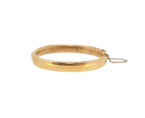 A hinged bangle, plain polished with a push-in clasp and safety chain, width 9mm, inside diameter 6cm, unhallmarked, stamped 