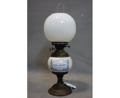 A ceramic and brass oil lamp, with opaque glass shade, with advertising for Solon Caddy's Fine Groceries, Wines &amp; C. &amp