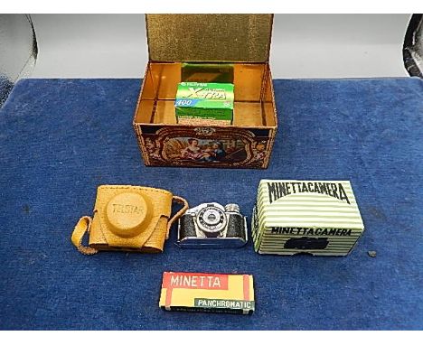Minetta mini camera with a box of exposures and a 35mm film in a tin