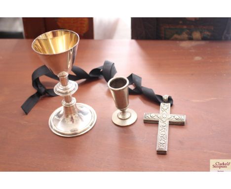 A white metal Communion Chalice; a white metal cross with foliate decoration and a small pewter candlestick