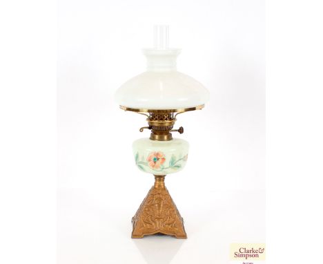 A Victorian opaque oil lamp and shade on gilded cast metal base