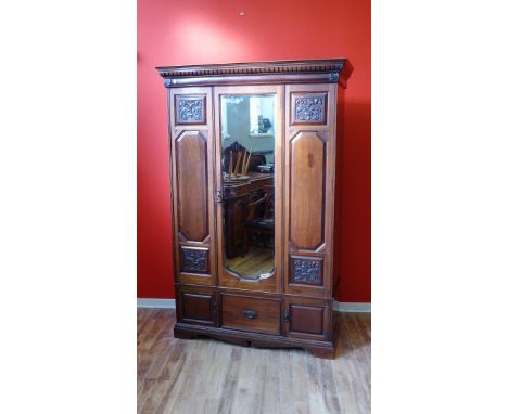 An Edwardian mahogany wardrobe with moulded cornice above mirrored panel door with fitted interior over one short drawer and 