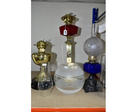 THREE OIL LAMPS, two with glass reservoirs, the tallest measuring approximately 54cm having a square brass column base, the o
