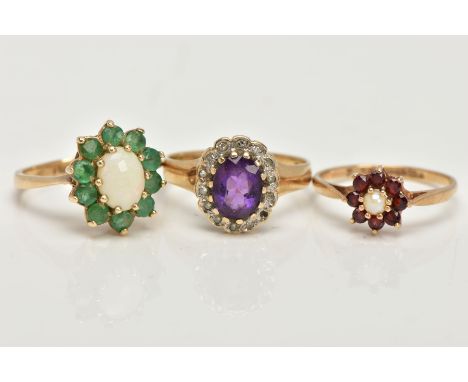 THREE 9CT GOLD CLUSTER RINGS, the first an oval opal set with ten circular cut emeralds, set in yellow gold, hallmarked 9ct L