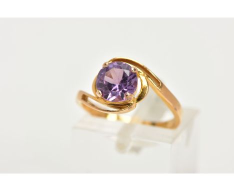 A YELLOW METAL GEM SET RING, a circular cut purple stone assessed as a synthetic colour change sapphire, set in an open work 