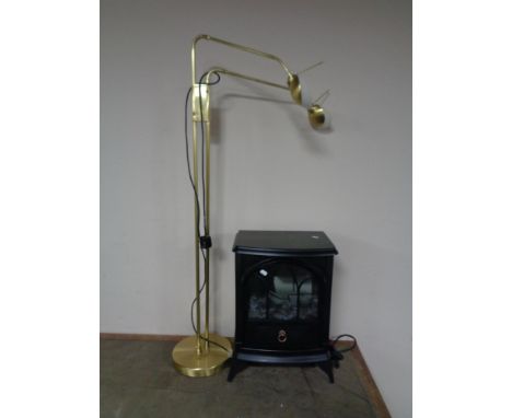 An electric heater in the form of a stove, together with a brass angle poise floor lamp. 