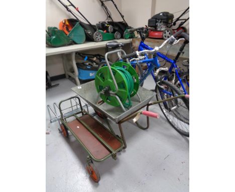 A metal wheelbarrow together with a folding sack barrow/trolley and a hose pipe on reel 