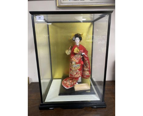 A contemporary matte-glazed Japanese doll/ornament, modelled as a young girl wearing a red kimono and elaborate head dress ho