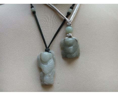 TWO CHINESE CELADON CARVED JADE FIGURAL PENDANTS, finely carved in shallow relief, one in the form of a standing boy, the sma