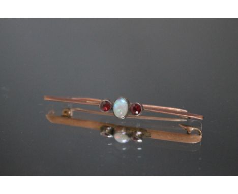 A 9CT GOLD BAR BROOCH WITH CENTRAL OPAL, the opal flanked by two pink gemstones, approx. 3.2 g