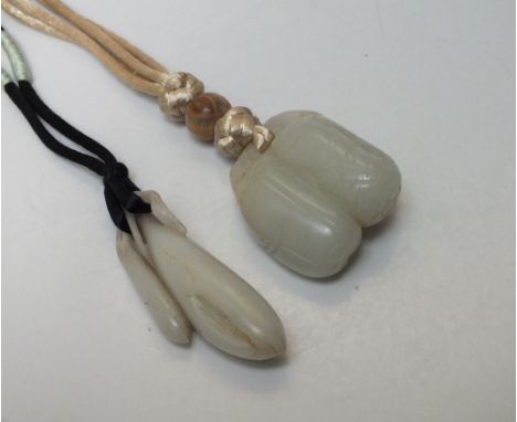 A CHINESE CELADON JADE PENDANT, finely carved in the form of seed pods, H 7 cm, together with a larger carved jade pendant (2