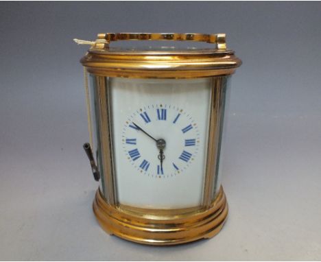 AN 8 DAY STRIKING OVAL CASED CARRIAGE CLOCK, the white enamel face with blue Roman numerals and minute markers, gold hour mar