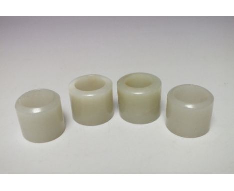 A COLLECTION OF FOUR CELADON JADE ARCHERS RINGS / THUMB GUARDS, each of plain form, tallest H 2.6 cm, largest overall Dia.3.1