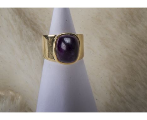 A retro 9ct gold and amethyst dress ring, the raised collet setting housing a cabochon domed purple stone on a thick band, 9g