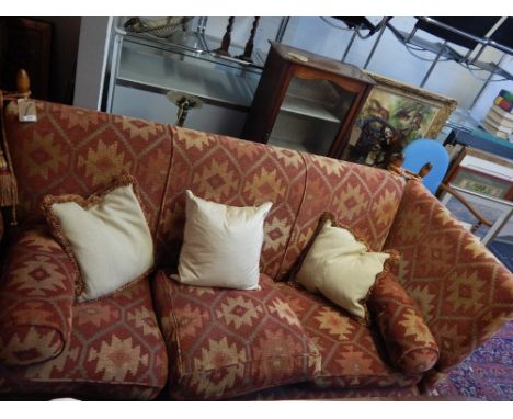 A contemporary Knole-end three seater sofa, upholstered in geoemetric designed terracotta fabric, cushion seats, raised on al