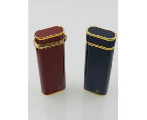 Cartier. A gilt metal and red enamel lighter, together with a gilt metal and blue enamel lighter. (2)