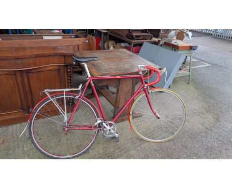 A vintage racing bike with red unmarked frame, Cinelli handle bars, French pedals etc.