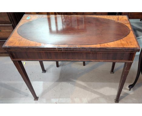 A 19th century Sheraton style mahogany fold over card table with wide satinwood crossband on square top legs.