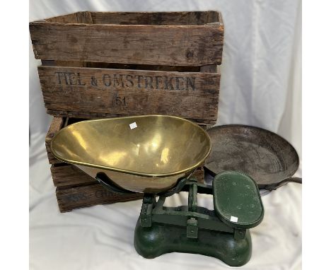 A set of grocers scales with brass pan; a large cast iron frying pan; two old wooden crates.