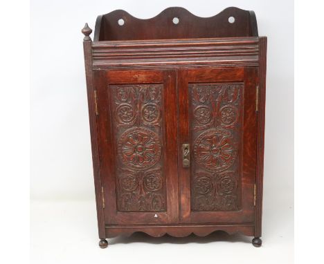 Carved oak smokers cabinet with pipe racks and two drawers, lacking one finial, H: 45 cm. Not available for in-house P&amp;P 