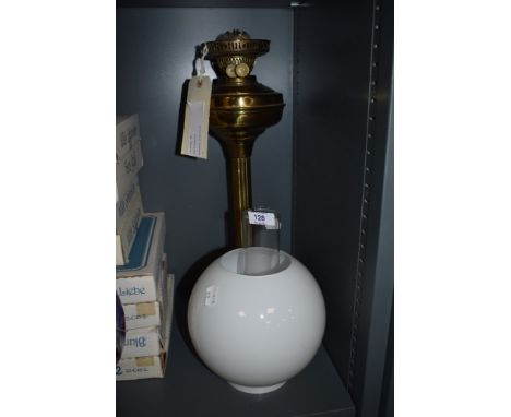 A brass oil lamp with chimney and shade.