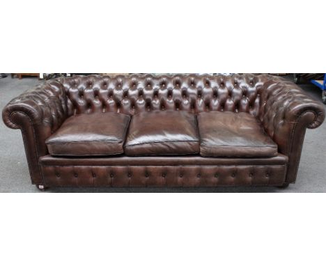 A brown leather upholstered button back Chesterfield sofa on bun feet, 228cm wide x 72cm high. 