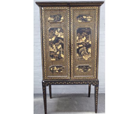 A 19th century Chinese export black lacquer chinoiserie decorated cabinet on stand, the pair of triple relief moulded panel d