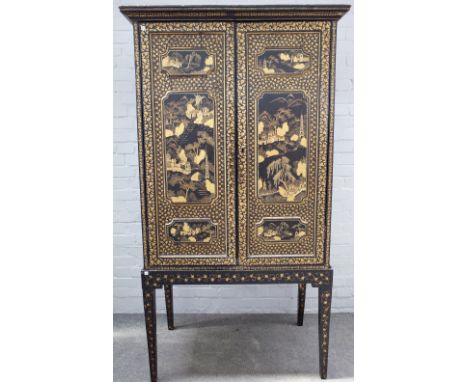 A 19th century Chinese export black lacquer chinoiserie decorated cabinet on stand, the pair of triple relief moulded panel d