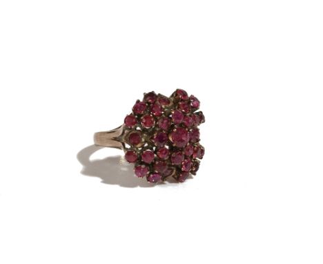 A gold and ruby cluster ring, claw set with circular cut rubies, in a raised design and with the principal ruby mounted to th