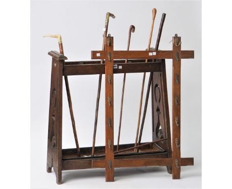 An early 20th century oak stick stand of Arts and Crafts style, 74cm high, containing five walking sticks and two leather bou
