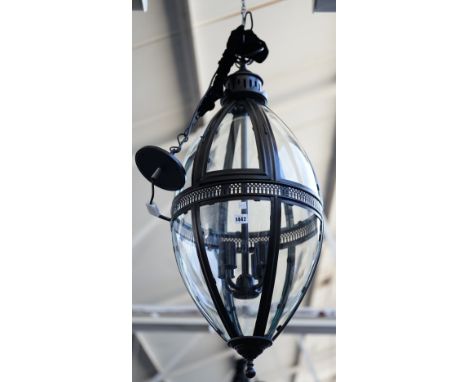 A pair of modern patinated metal lanterns of ovoid form, each with glazed panels, pierced central circlet and internal four l