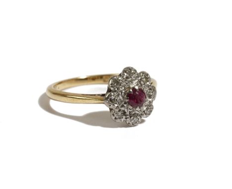 An 18ct gold ring, claw set with a circular cut ruby in a surround of eight circular cut diamonds, Birmingham 1962, ring size