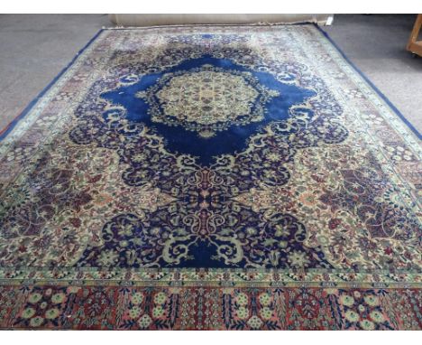 A Wilton carpet, machine made of Persian design, the dark blue field with bold centre medallion, 455cm x 320cm. 