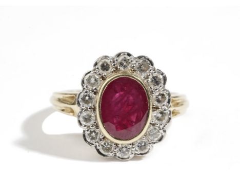 An 18ct gold, ruby and diamond oval cluster ring, collet set with the oval cut ruby in a surround of circular cut diamonds, b