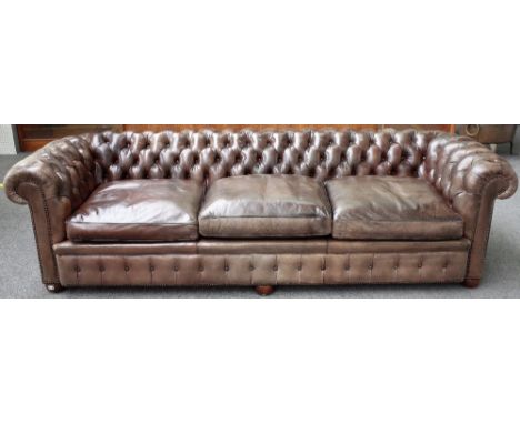 A large brown leather upholstered button back Chesterfield sofa, on bun feet, 260cm wide x 72cm high. 