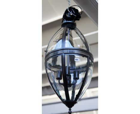A modern patinated metal lantern of ovoid form, with glazed panels, pierced central circlet and internal four light fitment, 