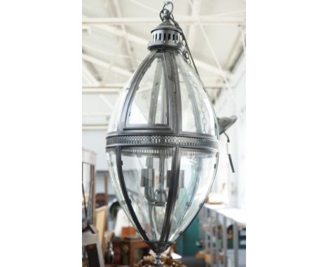 A modern patinated metal lantern of ovoid form, with glazed panels, pierced central circlet and internal four light fitment, 