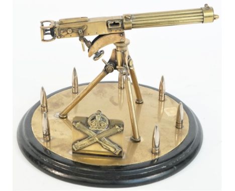 A brass model of a WWI Vickers machine gun, 20th century, on a tripod and circular base within a border of upturned bullets o